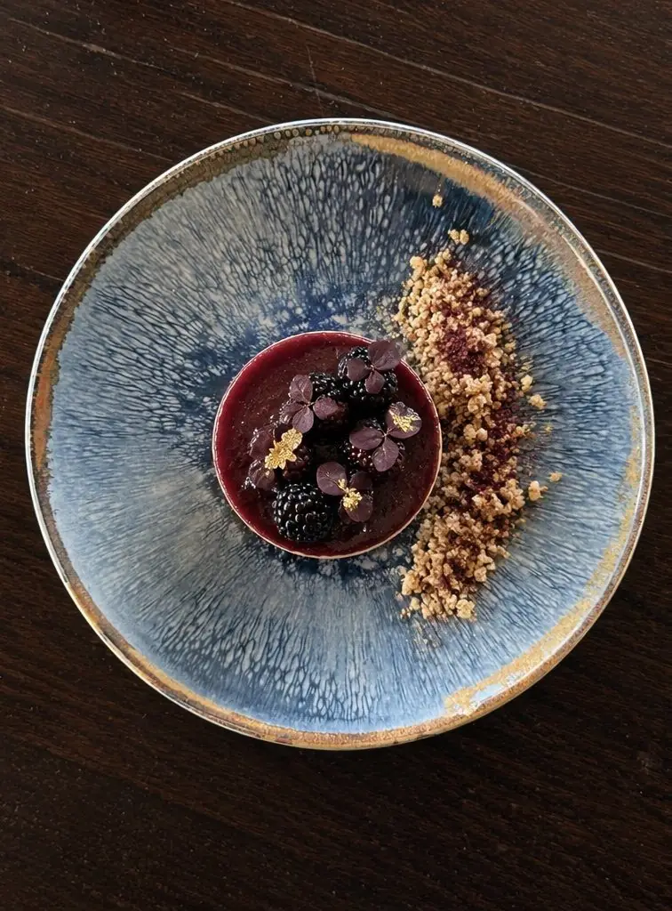 Berry dessert with blackberries and crumb on a blue glazed plate