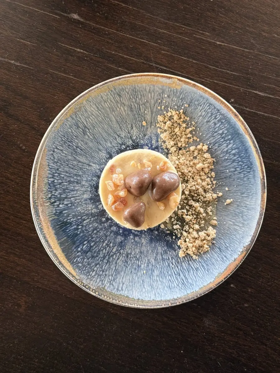 Caramel dessert with chocolate hearts and crumb on a blue glazed plate